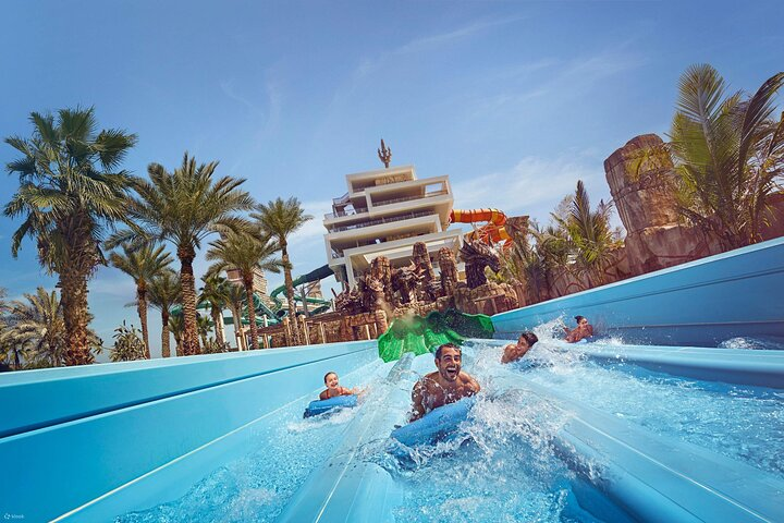 Experience the rush of water as friends zoom down exhilarating slides surrounded by lush palm trees creating unforgettable memories at Atlantis Aquaventure in Dubai's stunning seaside oasis.